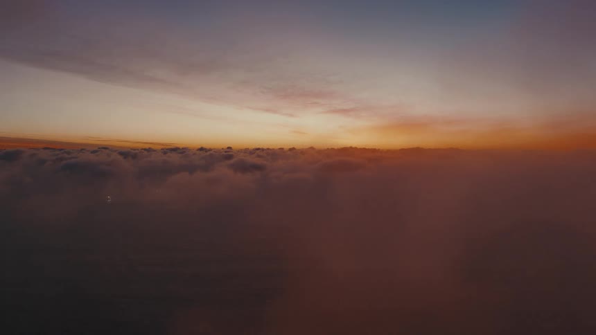 Sea of clouds under a sunset sky with color gradation on the horizon