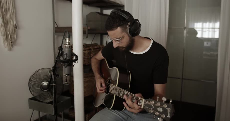 A man wearing headphones plays guitar
