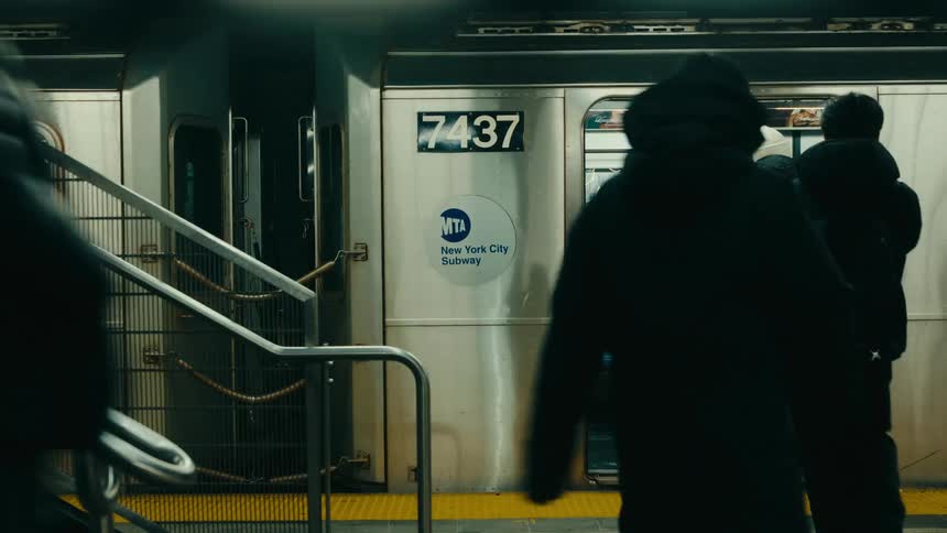 Four men walks across a subway platform and boards a new york city subway train as they enter the open doors of the silver car