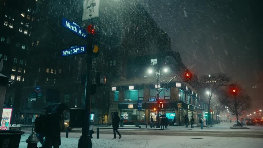 Pedestrians walk on downtown streets as snow falls on a winter night