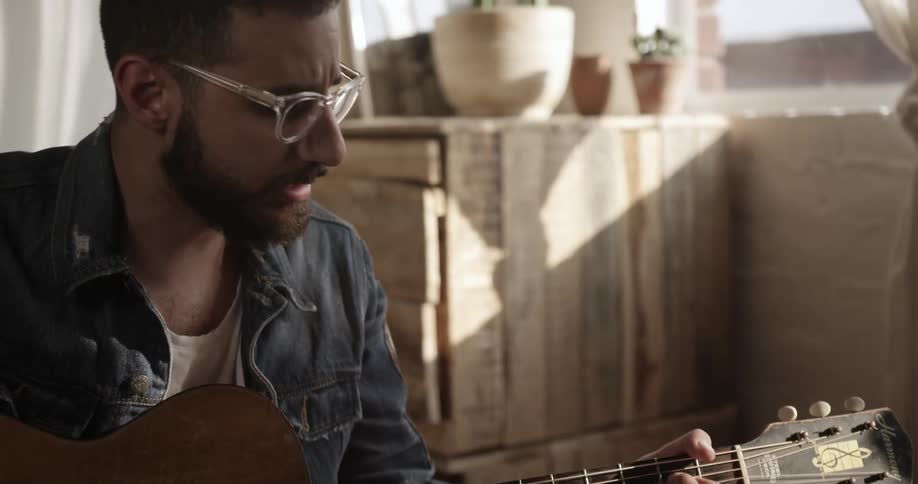 The man is playing guitar and also singing