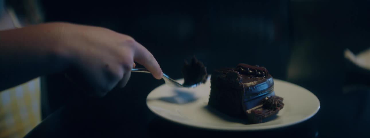 A child eating a slice of cake with a spoon from a plate in the dining room