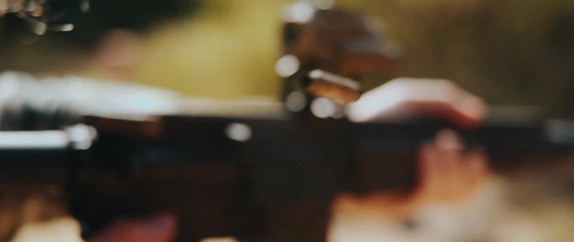 Hand on a rifle and a bullet shell flies into the air
