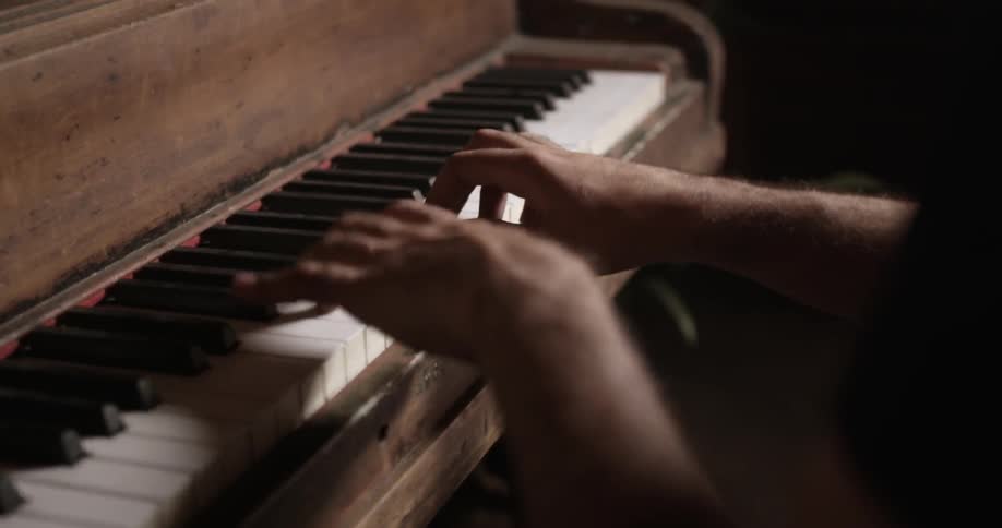 A person plays a wooden piano