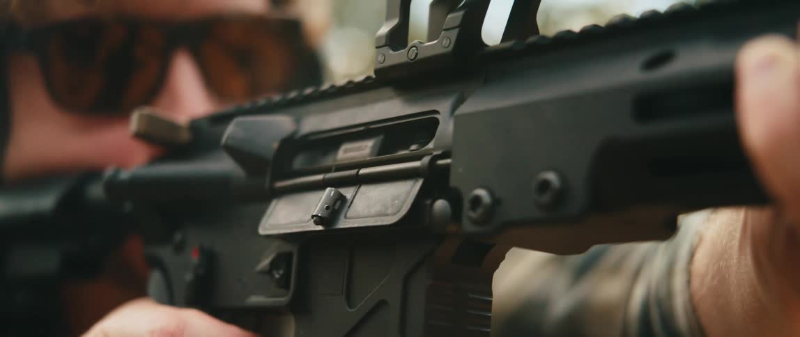 Man holds a rifle firing shots as bullet shells fly into the air