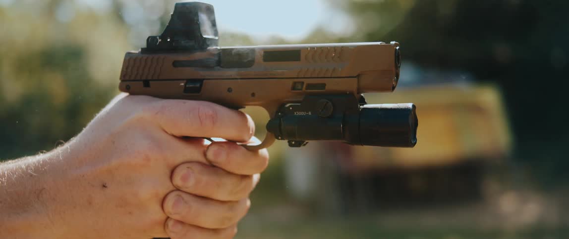 Handgun firing with a cartridge being ejected during slide recoil outdoors
