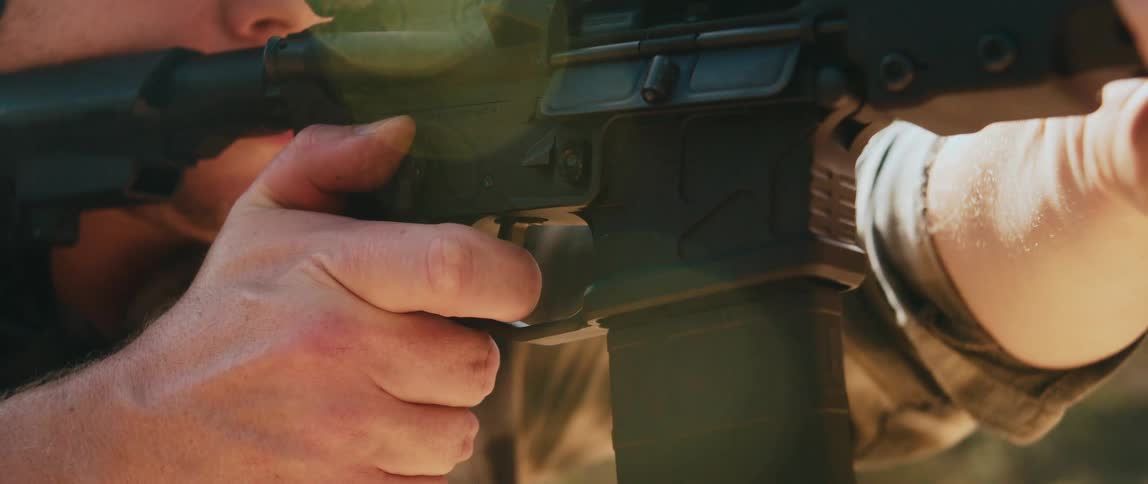 Person fires a semiautomatic rifle with finger on the trigger during outdoor shooting practice