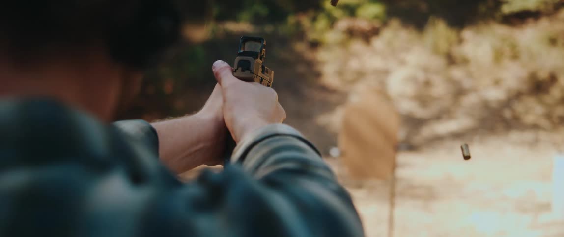 A man shooting a handgun outdoors at a range