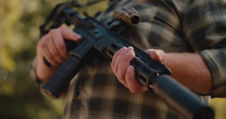 Closeup of a person standing outdoors holding a rifle