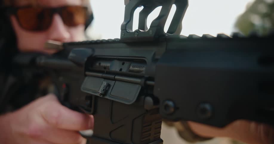 Person fires a rifle with mounted sight while maintaining a firm grip outdoors