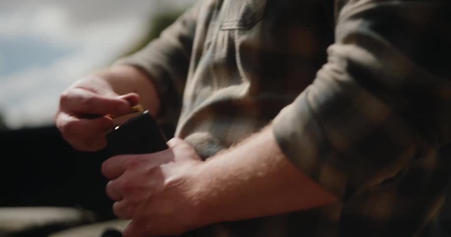 A man loading a gun magazine outdoors