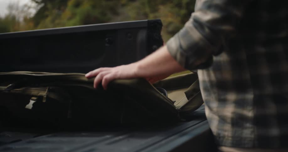 A man taking a gun out of a bag in a truck