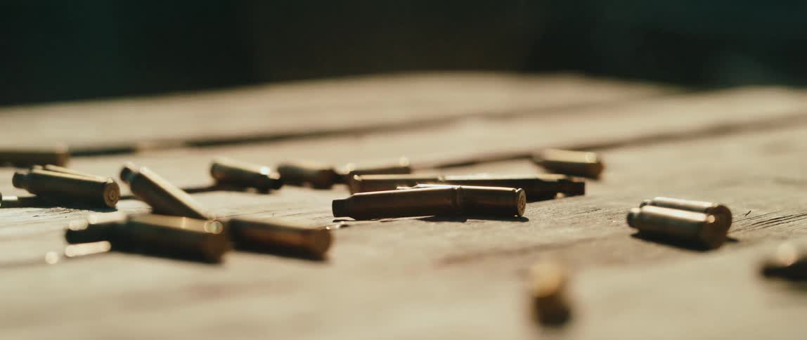 Closeup of spent bullet casings scattered across a wooden surface