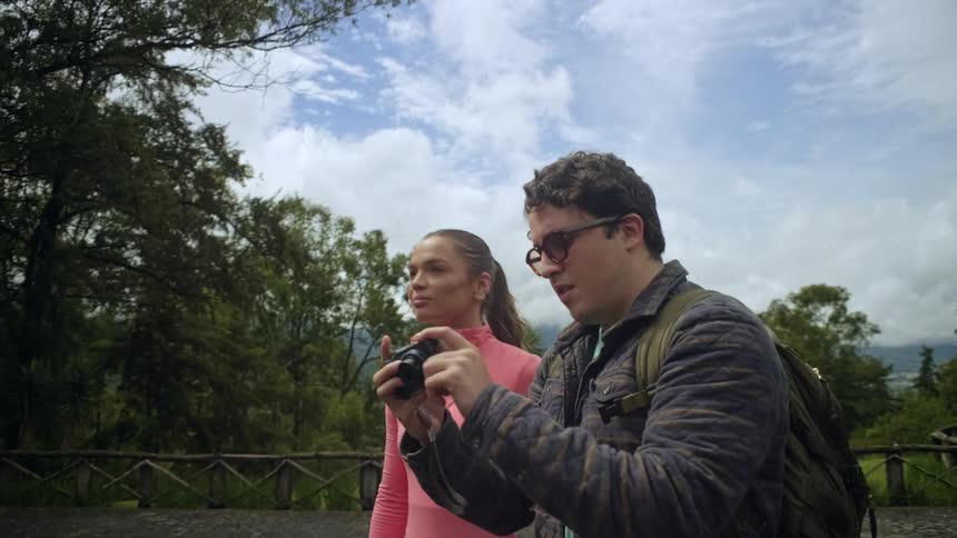 A man taking a photo and then showing the camera to a woman besides him