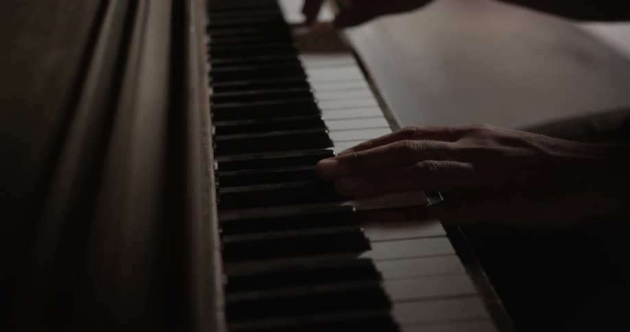A man is playing the piano in a dark room