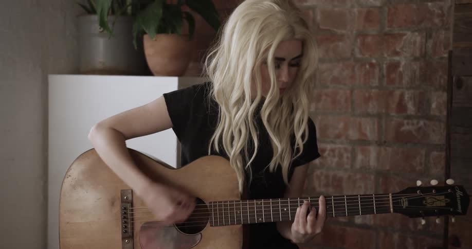 A woman with white hair plays guitar