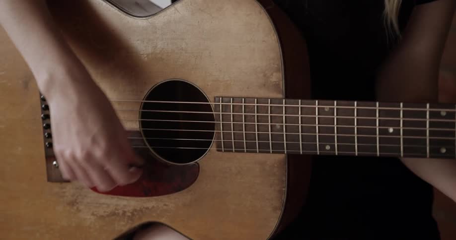 A woman strumming an acoustic guitar
