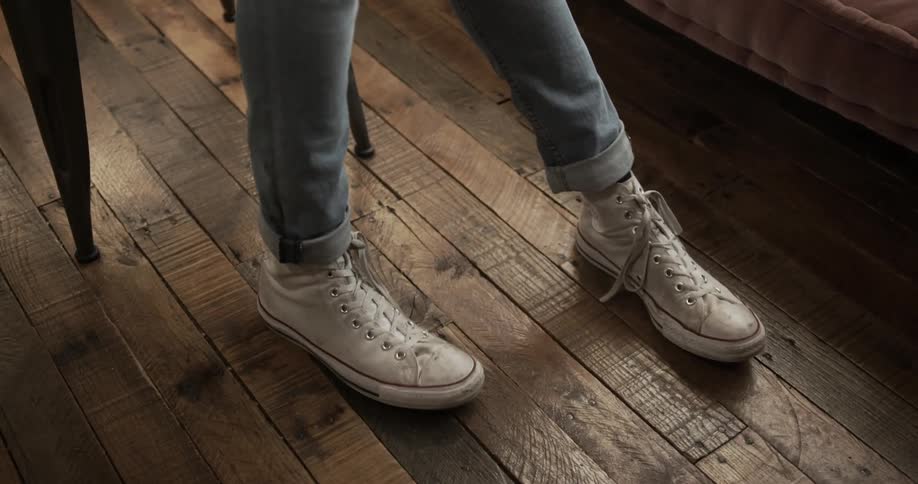 A person taps their foot on the wooden floor