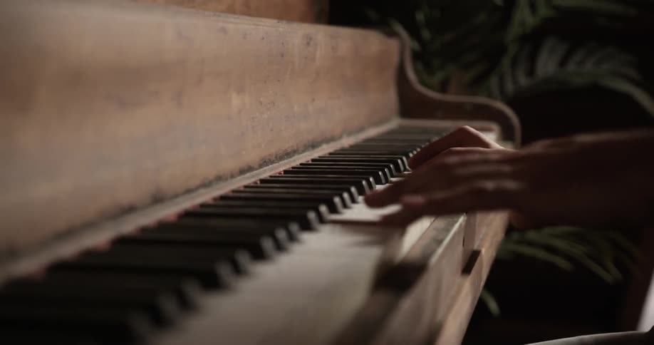 Hands play a piano indoors