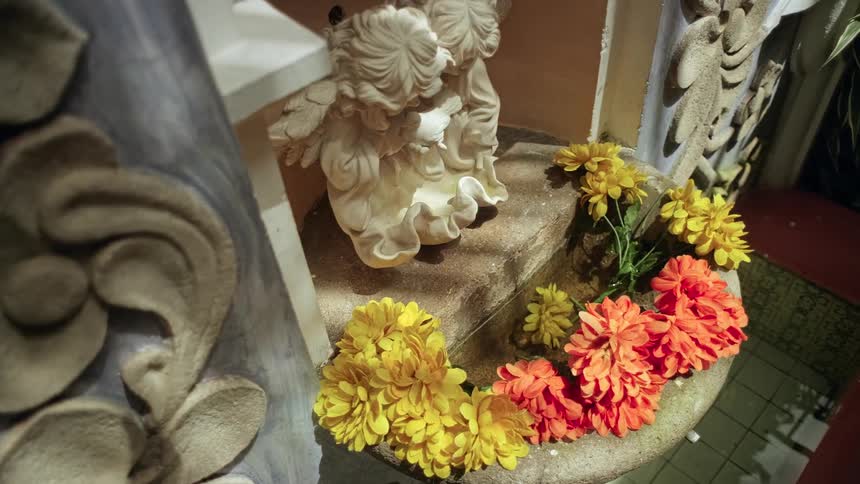 Decorative figurines resting on a stone base with yellow and orange flowers arranged around them