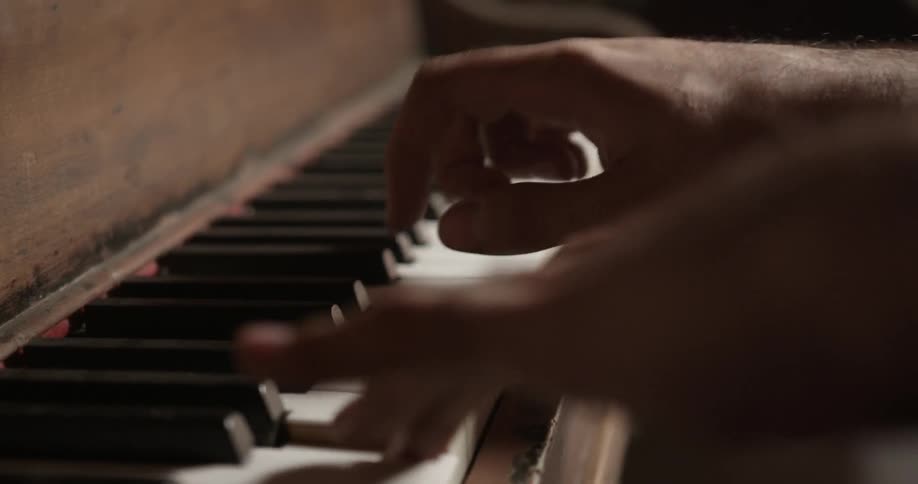 Hands play the keys on a piano