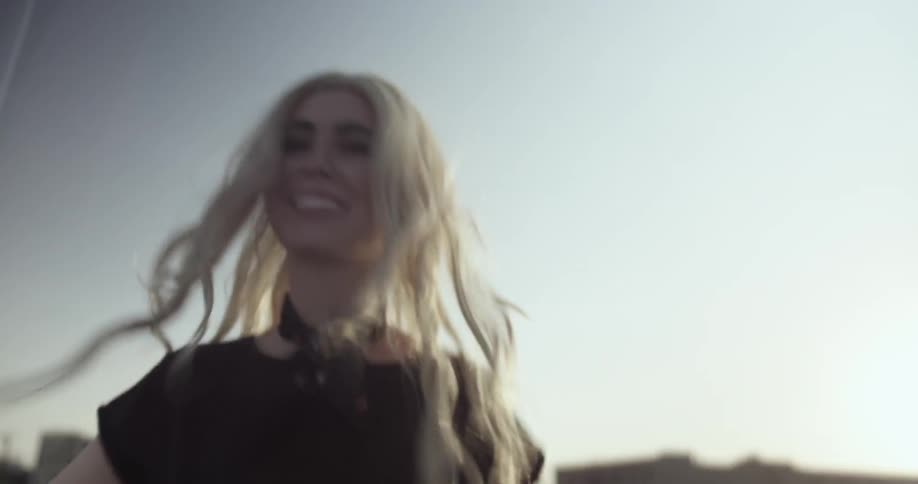Smiling woman spins around outside on a sunny day