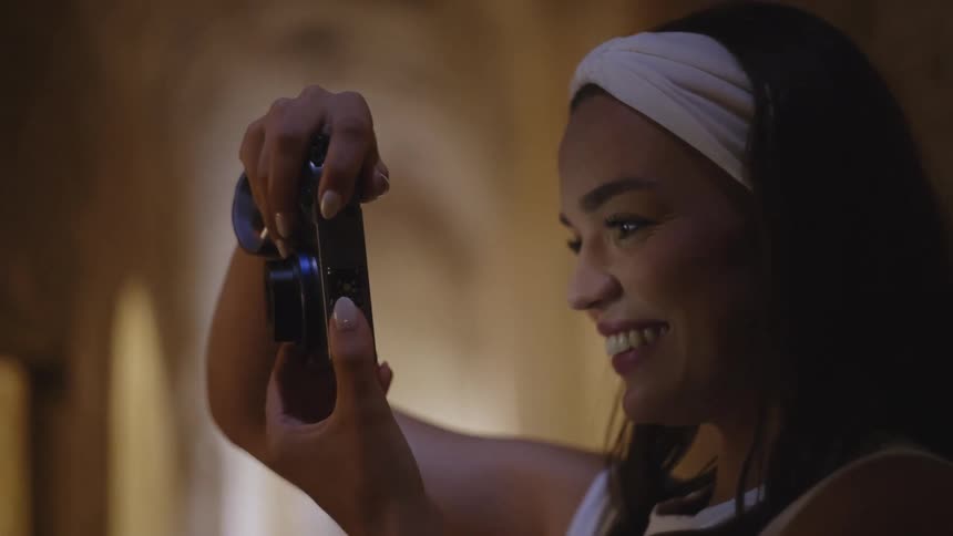The woman is smiling as she takes photos
