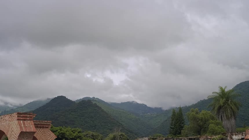 Mountain range covered by vegetation under an overcast sky with dense clouds