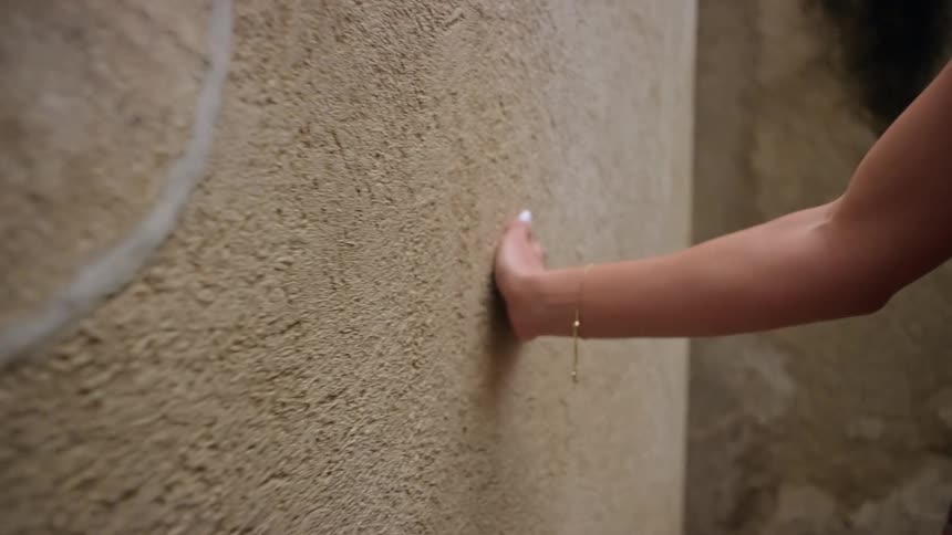 The woman traces her hand across the wall