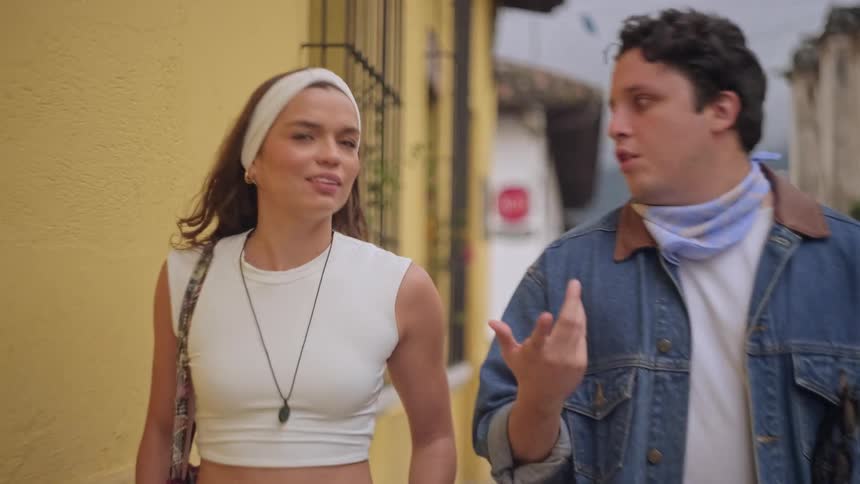 The man and woman talk while walking through the city