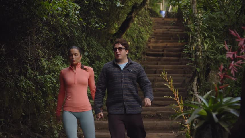 Man and woman hold hands as the walk down a staircase in the woods
