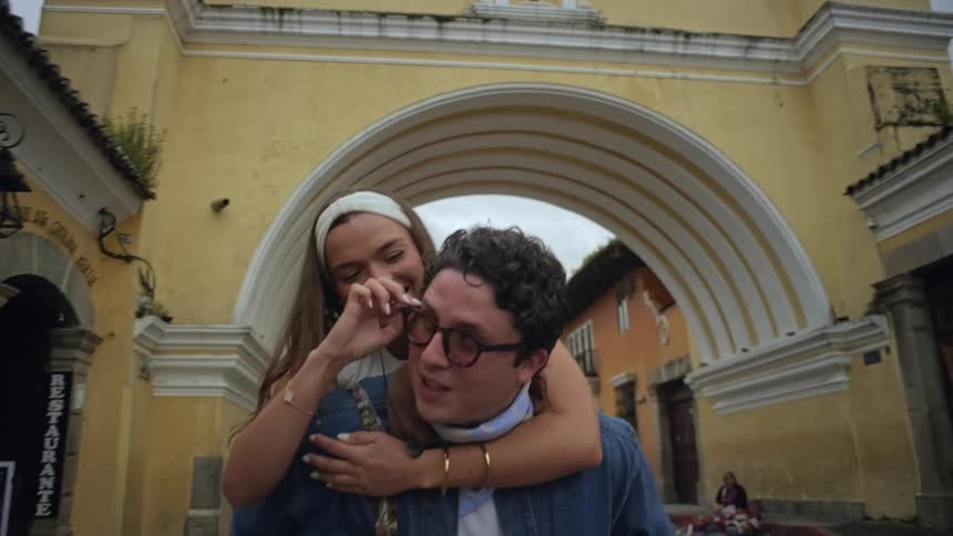 The woman is piggyback riding a man in the city
