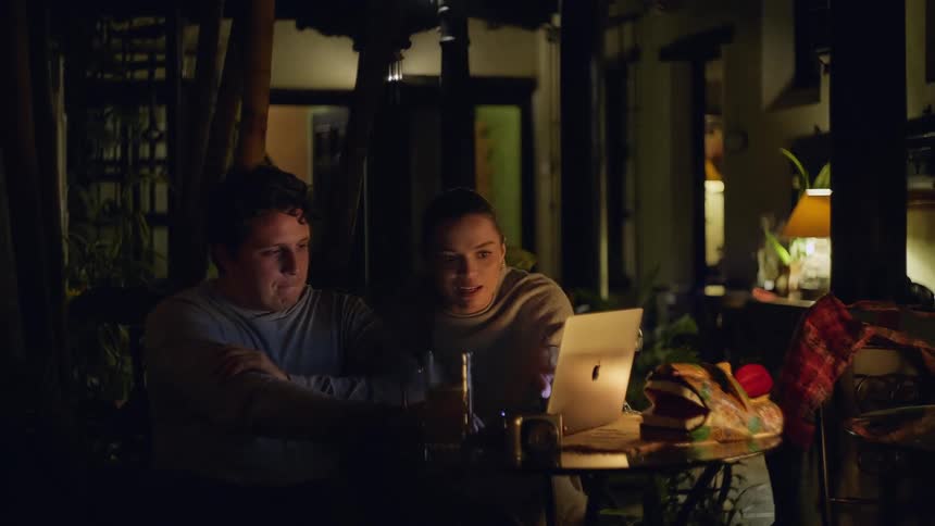 Young man and woman sitting at a table with a laptop computer and a mug of beer on the table