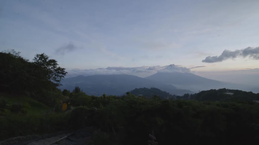 Mountain landscape at dusk with layers of vegetation and a clear sky in the background