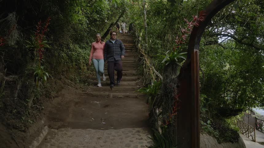 A man and woman holding hands walk along an outdoor set of stairs