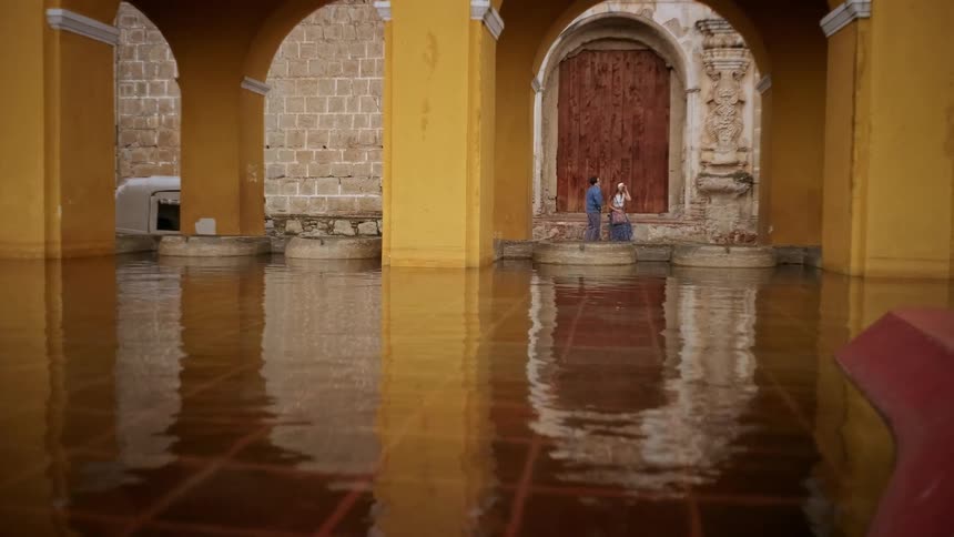 Two people running and sitting down facing a monumental area with water