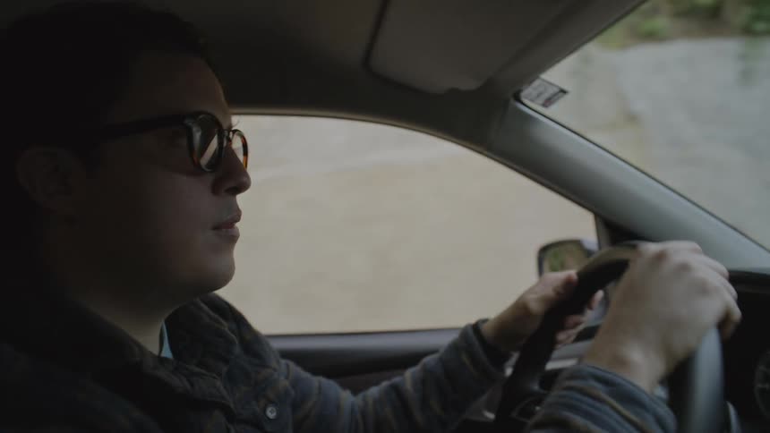 A man wearing sunglasses driving a car
