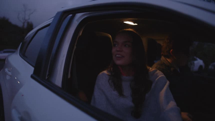A man and woman getting out of a car at dusk
