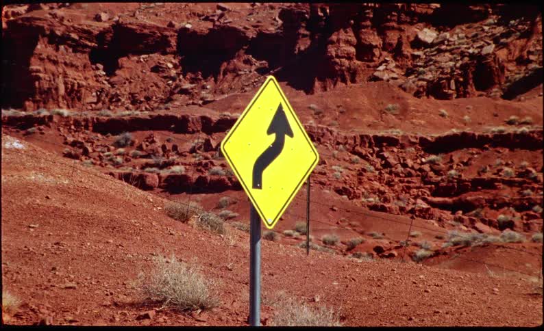 Road sign next to a desert area outdoors during day time