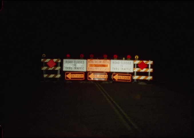 Road barriers with illuminated detour signs at night