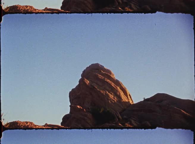 Mostly bare rock formations stand under a clear blue sky
