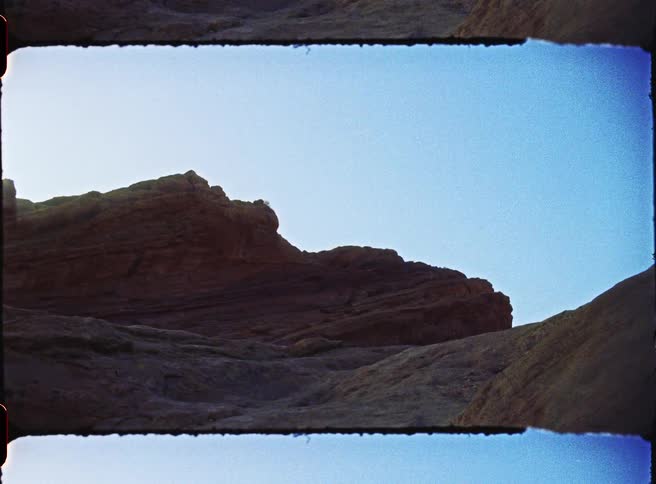 Reddish rock formations stand under a light blue sky