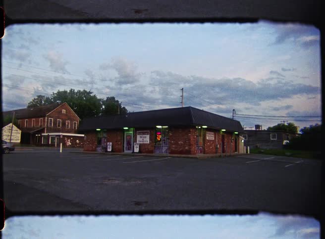 Corner store in a brick building viewed from a parking lot at dusk