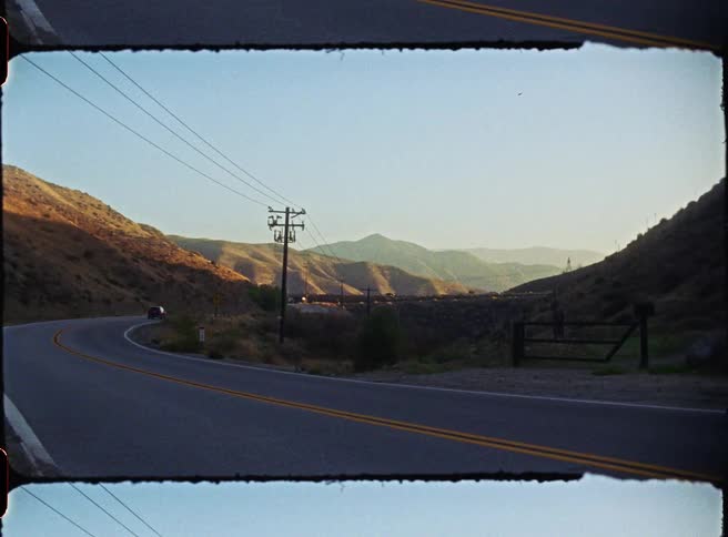 Winding road between hills with power poles along the route