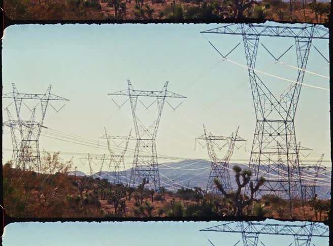 A group of electricity trellises stand on a hillside