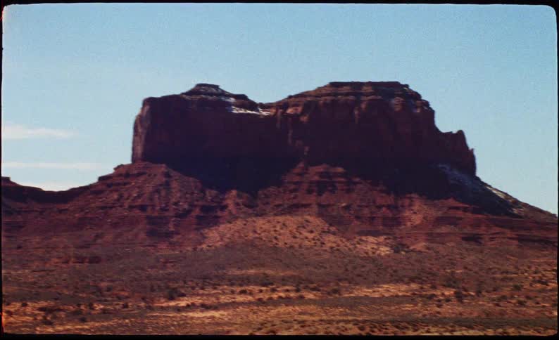 Isolated rock formation in a desert landscape under a blue sky