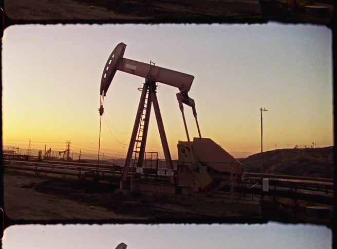 An old pumpjack is pumping for oil in the sunset