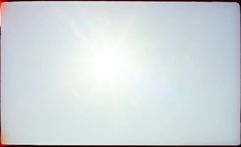 A bright sun shining in the clear sky above the woods on a sunny day