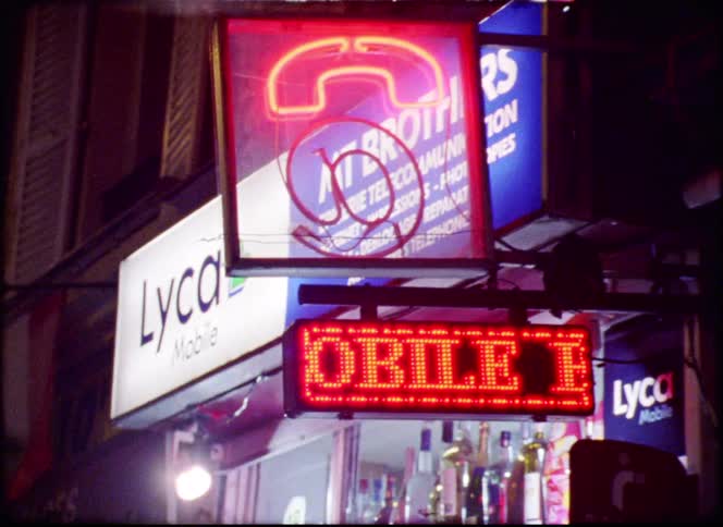 Illuminated shop and phone service signs on a commercial street at night