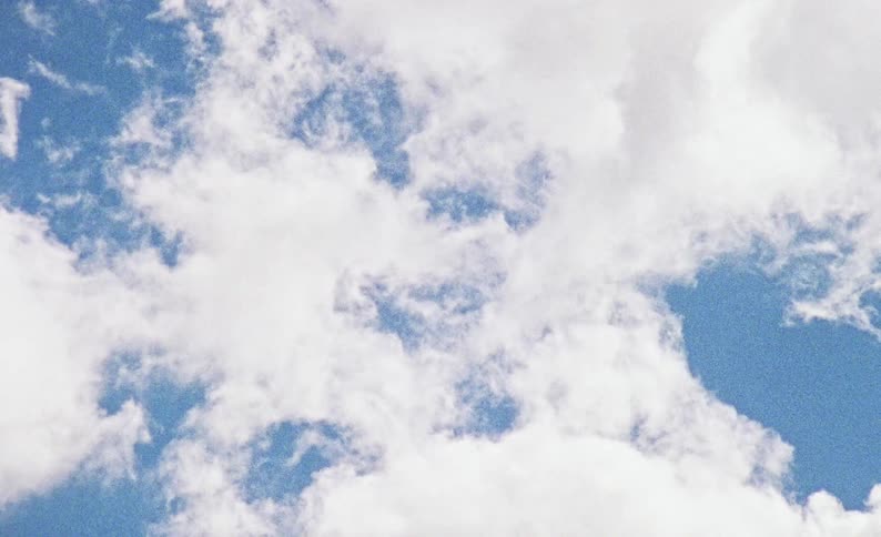 A soft jagged horizontal line is formed where the dense white clouds at the bottom of the frame meet the open blue sky above them